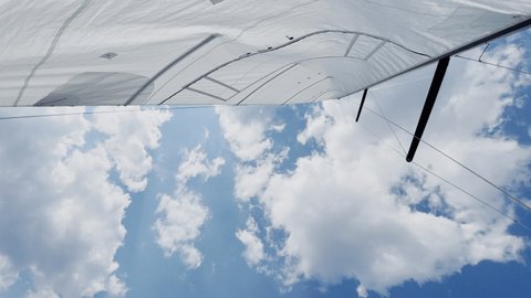 The bottom view on a mast of the sailboat, a sail are unfolded, mainsail, a clear sunny weather, the blue sky with clouds, 