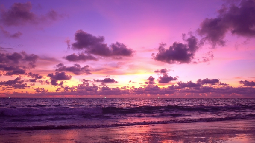 Dramatic sea sunset or sunrise Burning purple sky and shining white waves crashing on sandy shore Beautiful light reflection on sea surface Amazing landscape or seascape background