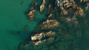 4K: Drone Aerial Clips of Jagged Rocks in Turquoise sea. Small waves hit the sharp stone. View from above, looking down. Stock Video Clip Footage