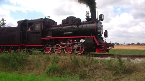 Vintage coal steam locomotive with smoke on trail. Retro transport and travel. Historic train on railroad.
