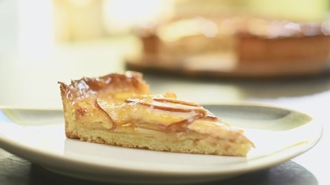 Confectioner serves piece classic french apple tart in a plate.