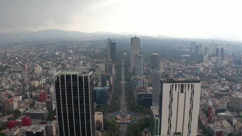 Backwards reveal of long straight boulevard lined by skyscrapers. Cloudy sky before rain or storm Mexico City, Mexico in 2021