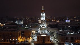 Dormition Cathedral illuminated in winter snowy evening lights. Aerial view Kharkiv city downtown, Ukraine. Fly up in sky