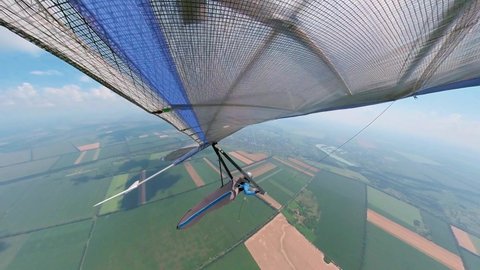 Hang glider soars under the clouds on high altitude