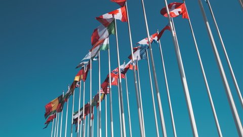 low angle view of flags of various UN members fluttering on wind against cloudless blue sky