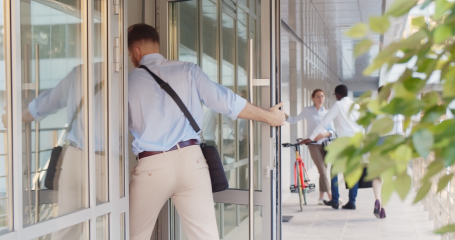 Young businessman entering business center. Caucasian handsome entrepreneur walking through entrance door of modern office building Royalty-Free Stock Footage #1076317328