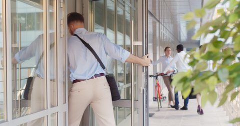 Young businessman entering business center. Caucasian handsome entrepreneur walking through entrance door of modern office building