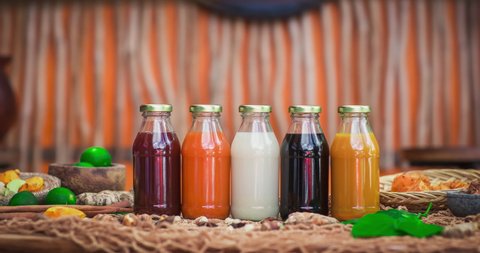 Stopmotion of many different Jamu drinks- Indonesian herbal beverage in glass bottles with natural ingredients: turmeric, ginger, lime, palm sugar, lemongrass, tamarind on wooden table. Healthy eating