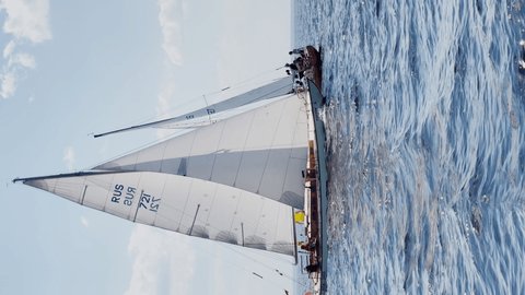 Russia, St.Petersburg, 20 June 2021: Regatta of sail boats at sunny day, boats run different tack, teams are preparing to put gennaker, the clear sky, sailing, reflection of sail on the water