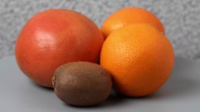grapefruit, orange, kiwi on a cutting board rotates on a turntable, top view, seamless video