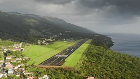 Panoramic view of short runaway for airplanes on green island of Sao Jorge at cloudy day, Azores, Portugal, Europe. Summer landscape with village located at atlantic ocean, 4k footage with copy space