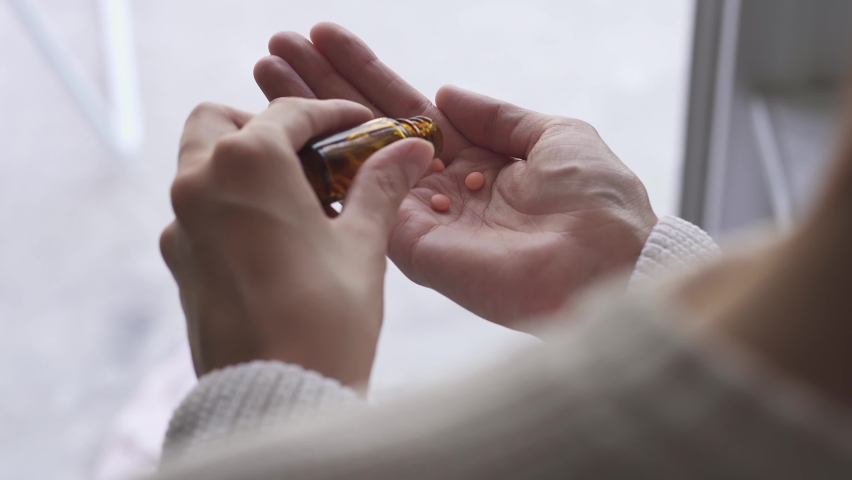 Take antidepressants, medicines, capsules, tablets at home. Orange pills spilled from brown bottle. Healthcare, health, medicine concept Sick woman takes pills, medications, antibiotics, pain reliever