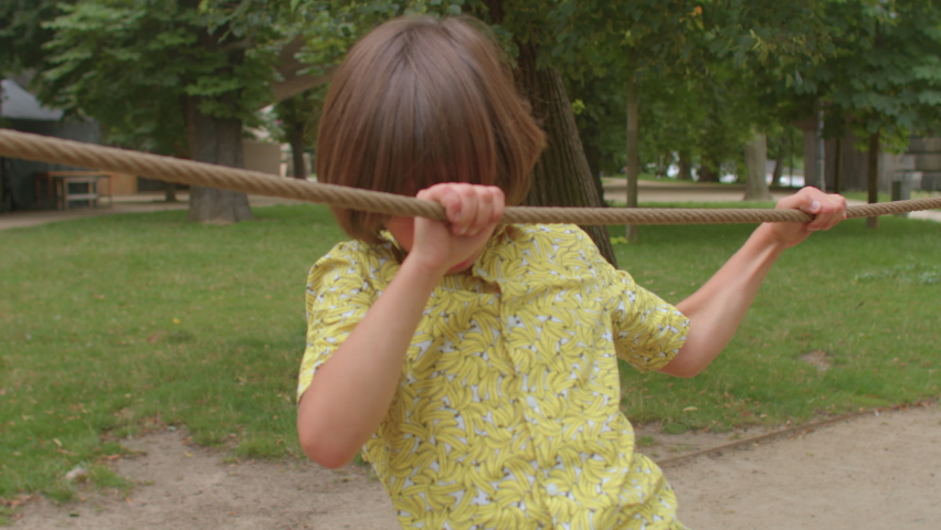 Young boy holds rope with hands and moves. Dexterity training, movement coordination. Active holidays at your leisure. Coordination training, hand strength. Unplugged time, kids outdoor play.