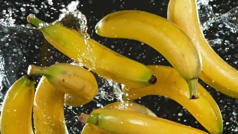 Super Slow Motion Shot of Flying Fresh Bananas and Water Side Splash Isolated on Black at 1000 fps.