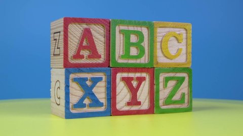 ABC and XYZ wood block on yellow surface.