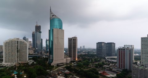 Jakarta, Indonesia - July 01 2021: The sun sets over Jakarta modern downtown and business district in Indonesia capital city. Shot as a day to night time lapse