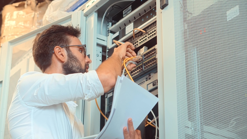 It Administrator In Mining Server Room And Connecting Ethernet Wire. Internet Network Switch With Plugged Ethernet Cables. Server Rack System Diagnostic Maintenance. Cloud Computing Mining Equipment Royalty-Free Stock Footage #1076345306