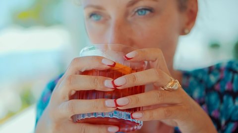 Woman Drinking Alcohol Negroni Cocktail Liqueur In Bar. Summer Holiday Vacation Travel On Sea. Girl Hiding From Sun Drinking Sipping Refreshing Appetizer Cocktail Liquor.Lady Drinking Negroni Cocktail