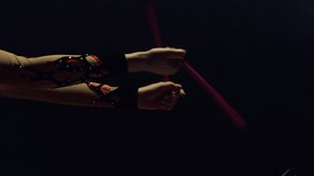 Closeup woman hands twisting gymnastic maces in dark space. Unknown girl arms exercising with sports equipment indoors. Unrecognizable female gymnast doing rhythmic gymnastics inside.