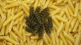 Closeup of uncooked macaroni with green spiral shaped macaroni in the center
