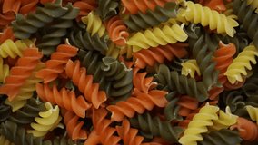 Close-up from above of uncooked colorful vegetable macaroni pasta in rotation 