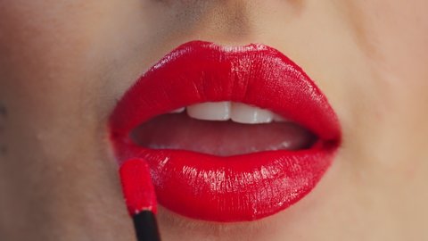 Macro Close-Up of a Beautiful Caucasian Woman Fixing Her Make-Up with a Red Lipstick Look.