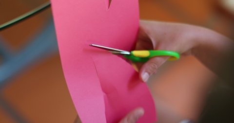 Child hands closeup cutting paper with scissors. Imaginative kid crafting