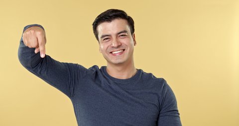 Cheerful smiling Hispanic man pointing hands downwards to empty space in front of him that can add your texts