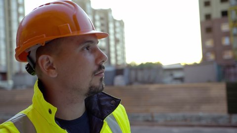 Smart look of a young worker, orange helmet, black beard, yellow sleeveless
