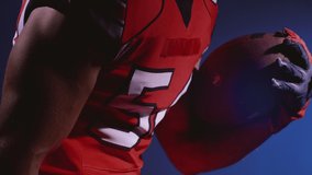 Faceless determined professional American football player in helmet holding a ball in hands. Confident man in red and white uniform. Usa game and extreme sport spirit concept. - Powered by Shutterstock - Get 15% off with code: PIKWIZARD15
