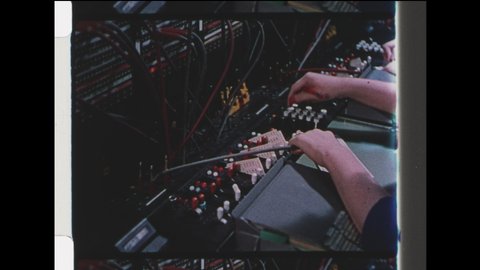 1940s New York, NY. Woman Telephone Operator at Switchboard Talks on Headset. Close Up of Woman's hands plugging in cables on telephone switchboard. 4K Overscan of Archival 16mm Film Print
