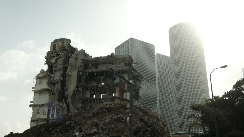 A wide view of an urban scene, where 3 high rises buildings are in the background, while a partly demolished building is standing in the foreground. a 4K video clip, Tel Aviv, Israel.