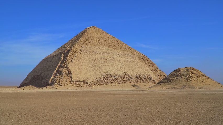 The Bent Pyramid is an ancient Egyptian pyramid located at the royal necropolis of Dahshur, approximately 40 kilometres south of Cairo, built under the Old Kingdom Pharaoh Sneferu. Egypt Royalty-Free Stock Footage #1076367509