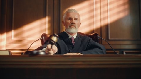 Court of Law Trial: Portrait of Impartial Judge Reading Decision, striking Gavel. Justice Pronouncing Sentence. Judgment after Deliberation. Guilty, Not Guilty Verdict. Cinematic Concept Rule of Law