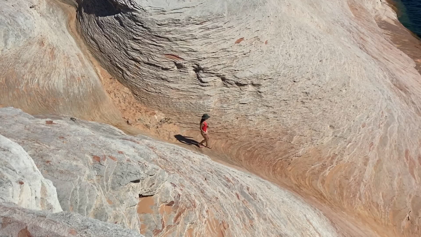 Camping by Lake Powell, Arizona USA. Top View of Female in Swimsuit Walking Down Rocky Hill to Tent and Kayak on Scenic Coastline on Sunny Day