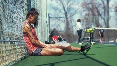 Female tennis athlete feeling dejected after an injury with ice on her knee