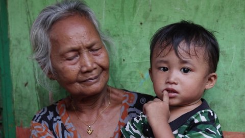 MAKASSAR, INDONESIA - JULY 23 2021: A grandmother with her granddaughter. Portraits of poor people