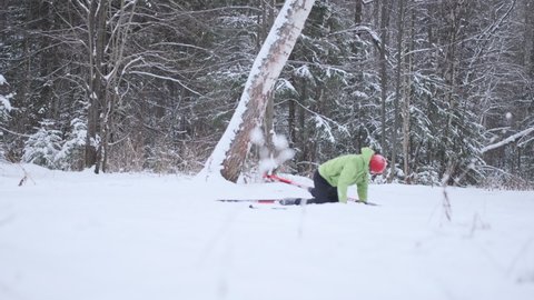 Cross country skier falls in the forest. Young man works out in the snowy winter forest with skating ski and falls