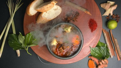 Top down view of Beef hotpot on a wooden board with spices, bread and vegetables. Traditional Vietnamese beef stew in red wine sauce (Bo sot vang). Asian food style decorated table 