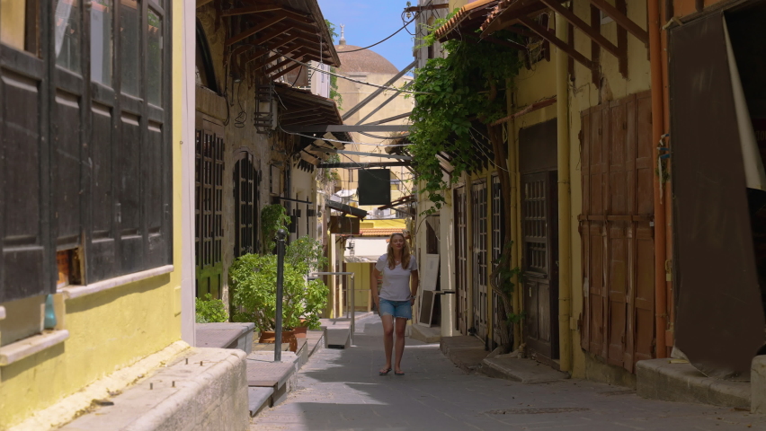 Female traveler walking down a historical narrow old street in the old town of Rhodes, a Greek island in the Mediterranean, Europe