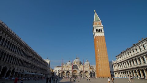 The famous St Mark's square (Piazza San Marco) in Venice, Italy during the day. Panning shot with an impressive view of the basilica, the church tower, and the palace with few tourists. 4K.