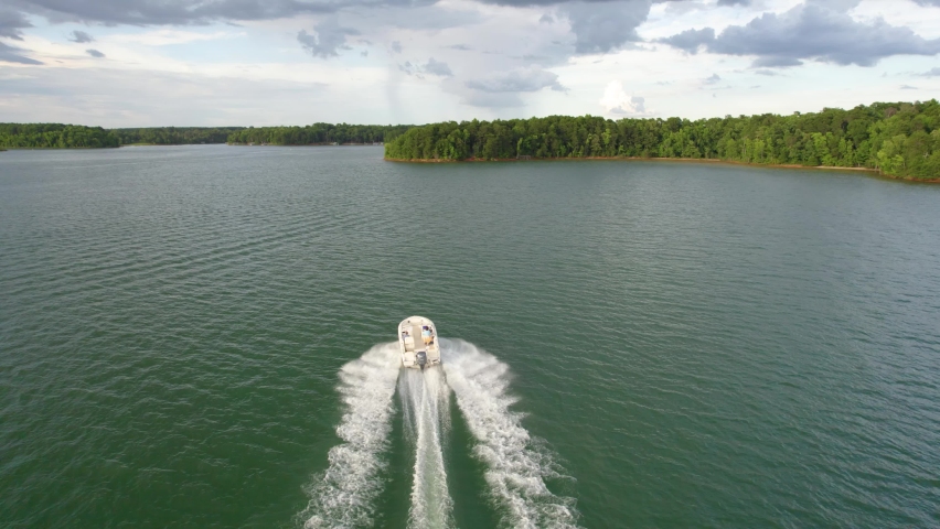 Aerial view of lake and boat running in the water. Green lake with green trees in the summer