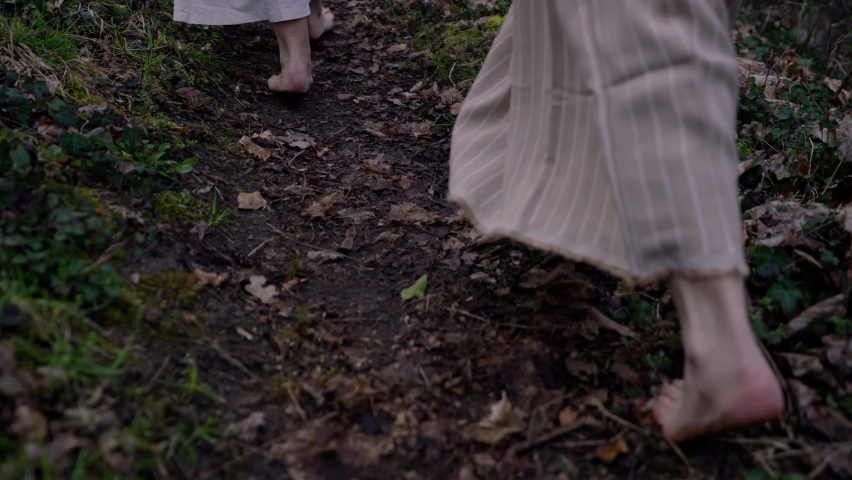 barefooted women walking on a path early in the morning with white robes and jars in their hands. Royalty-Free Stock Footage #1076397428