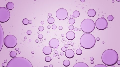 Purple different sized transparent bubbles move slowly and spontaneously in clear liquid on light purple background | Background for skin care lotion with glycerol advertising shot