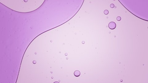 Big purple bubble moves to the left and down in transparent liquid with smaller ones on pale violet background | Background for skincare cosmetics commercial shot