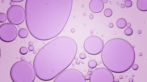 Big purple clear bubbles move slowly from the center in transparent fluid being replaced by small ones on light violet background | Background for skincare gel commercial