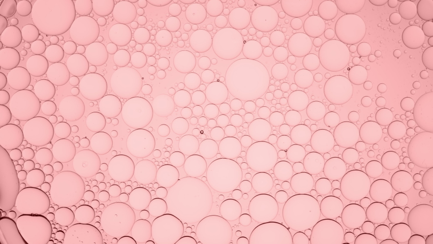 Big clear bubble moves along pale pink smaller ones moving them and explodes on pale pink background | Macro shot of moisturizer with glycerin for its commercial Royalty-Free Stock Footage #1076399921