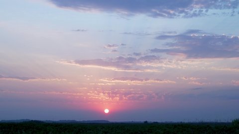 Beautiful Sunset 4K of the Sun, Colorful Sky and Clouds, Time Lapse. The Sun Sets below the Horizon in the Field. Beautiful Landscape, Colorful Sunset, Timelapse.