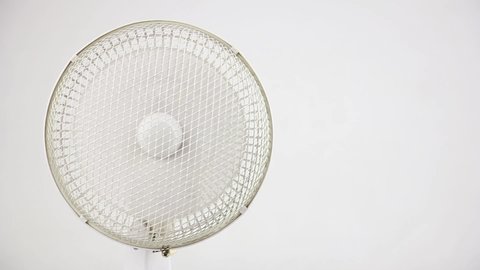 rotating white fan ventilator on left side on white background, electrical air conditioning and summer cooling, close-up front view