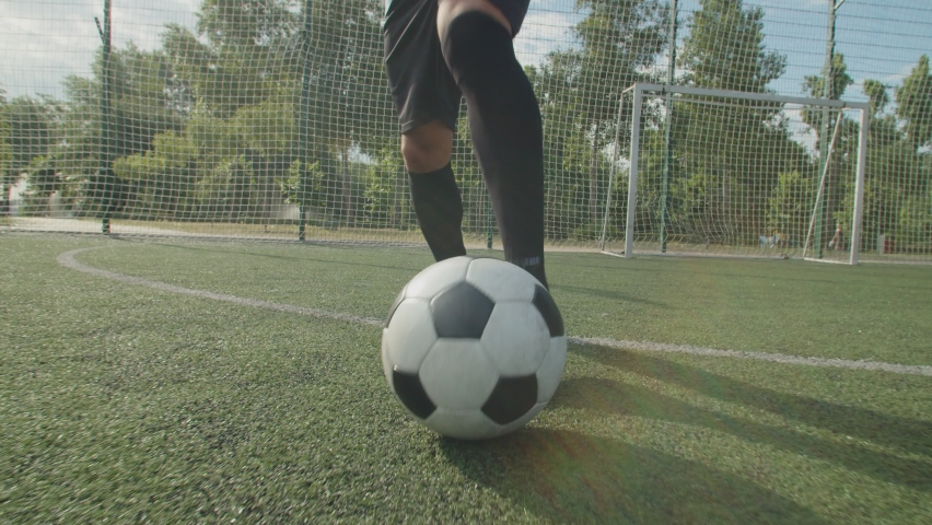 Close-up front view of soccer player legs in football boots and sportswear, dribbling, demonstrating close ball control, quick feet, performing football tricks and moves on football pitch at daybreak Royalty-Free Stock Footage #1076410637